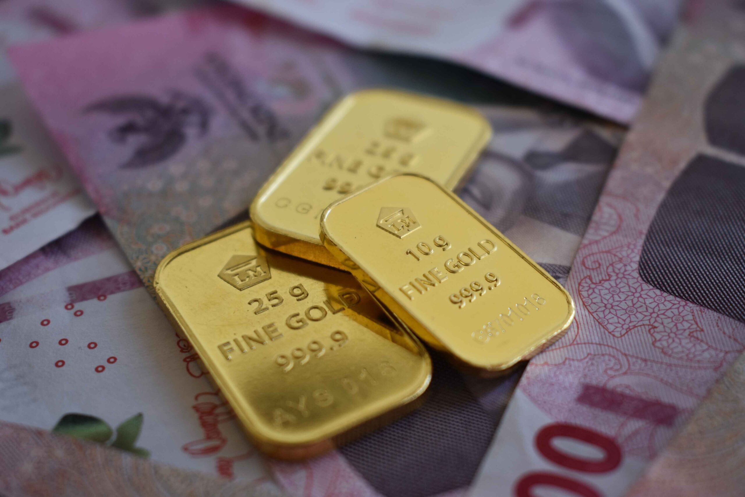 Warsh Kejutkan Pasar, RI Akhirnya Punya Gubernur BI Baru Detailed gold bars layered over Indonesian currency, highlighting wealth and investment.